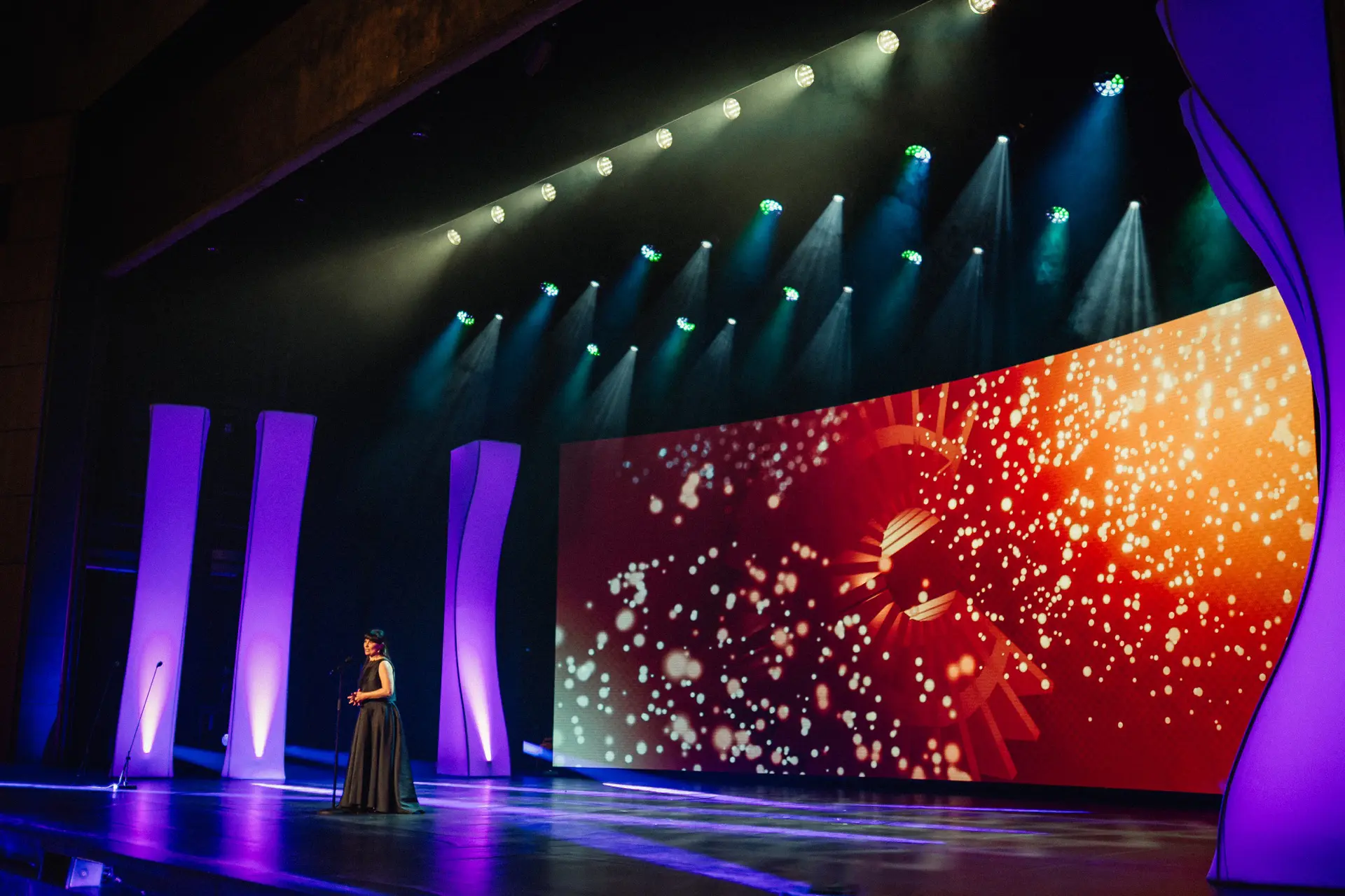 Apresentadora em palco de gala com ecrã LED e estruturas roxas, cerimónia dos Prémios Sophia