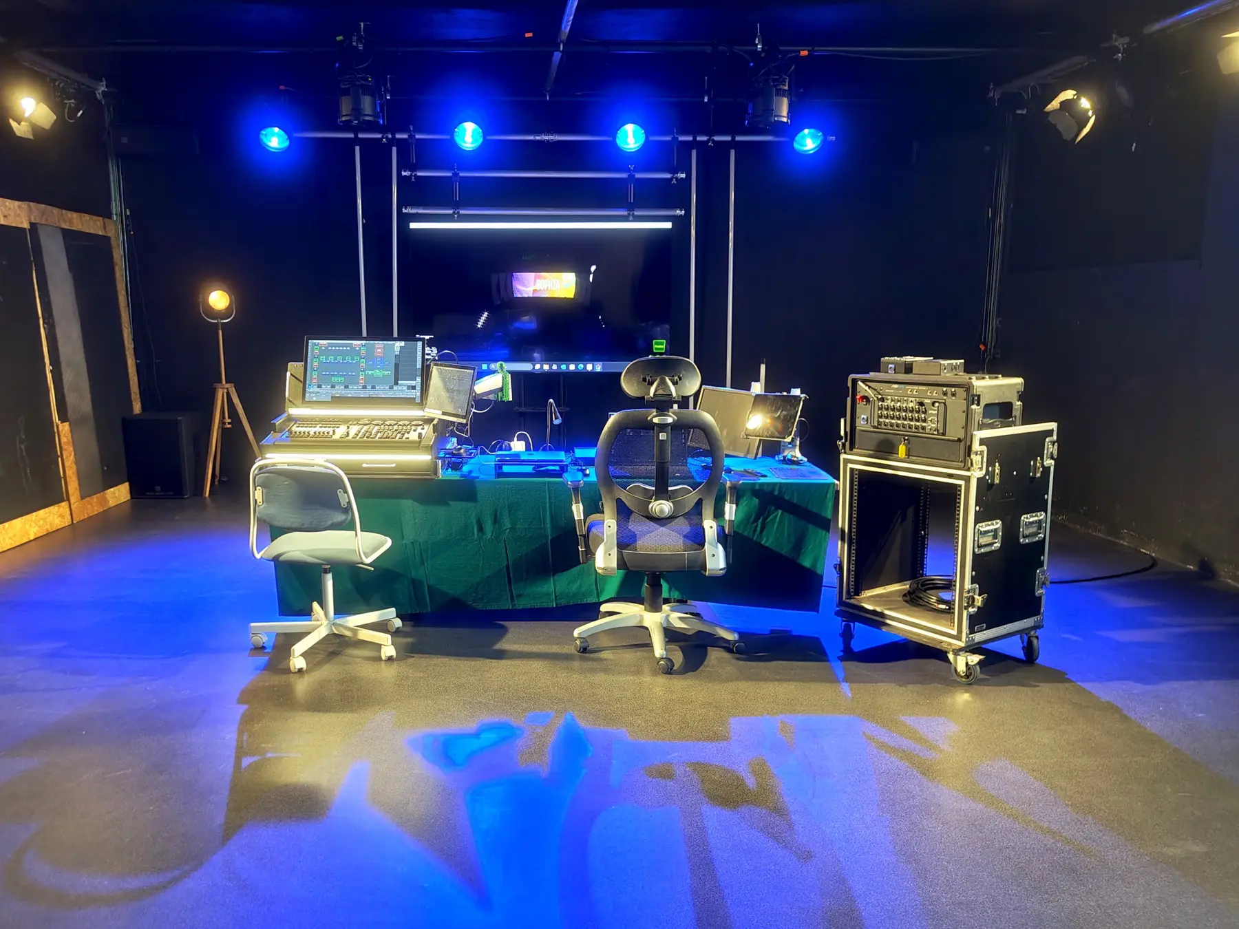 Mesa de operação de luz com monitores e rack de equipamento, iluminação azul no palco